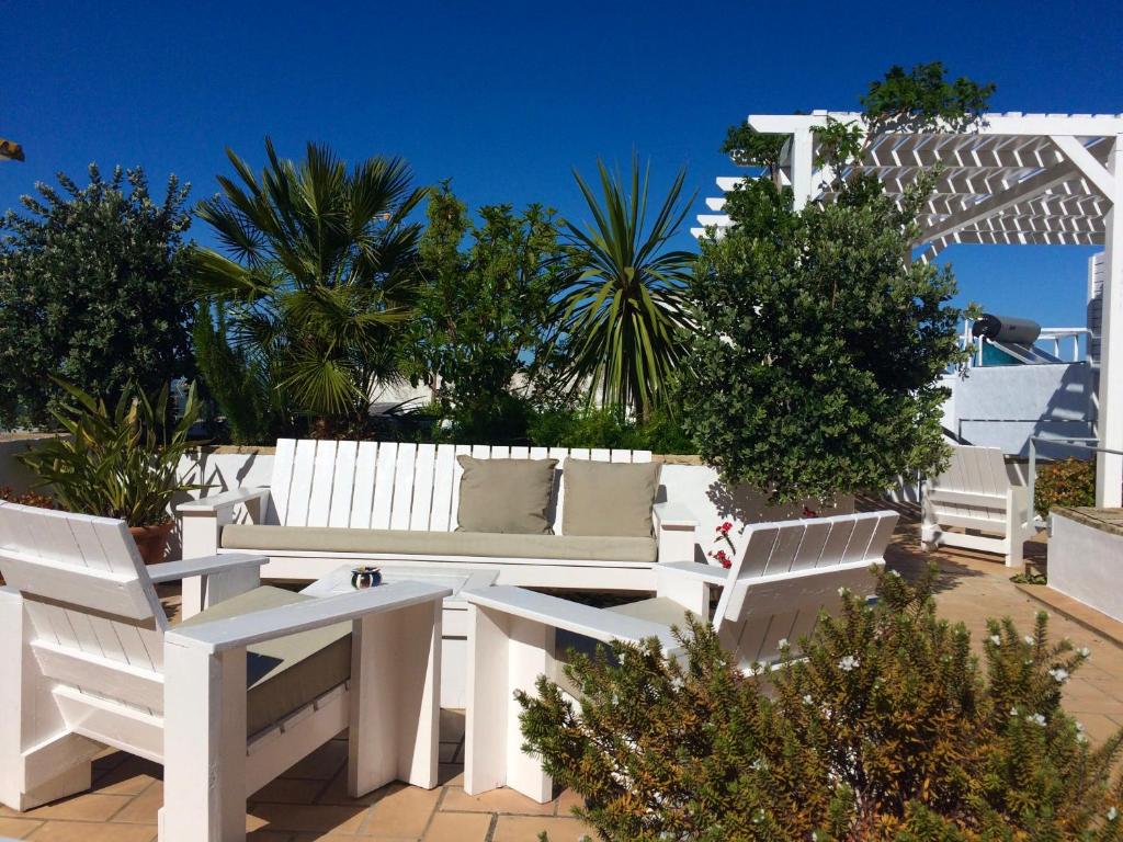 una panchina bianca seduta su un patio alberato di Siete Balcones y un patio a Vejer de la Frontera