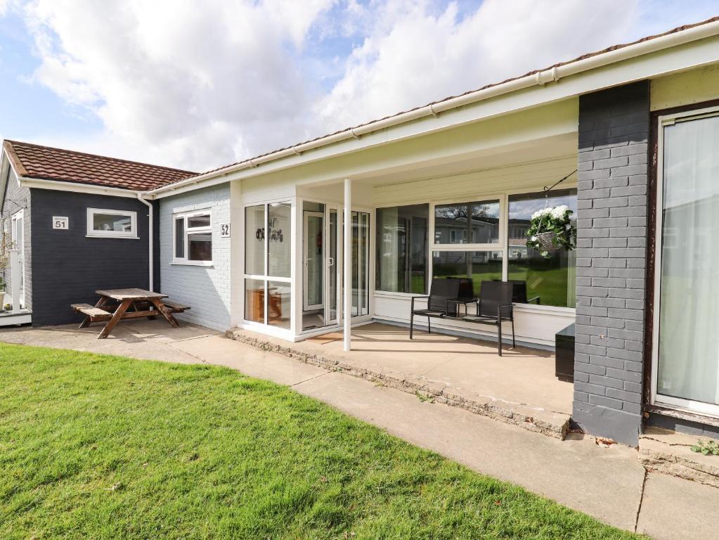 a house with a patio with a table and chairs at Marsh Bungalow in Carlton Colville