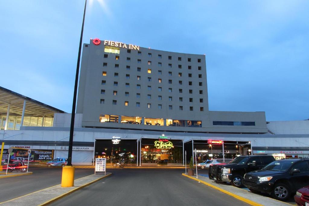 een hotelgebouw met auto's geparkeerd op een parkeerplaats bij Fiesta Inn Durango in Durango