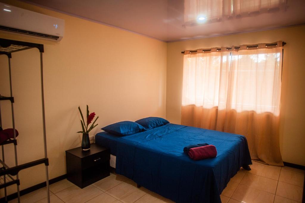 um quarto com uma cama com lençóis azuis e uma janela em Apartamentos Playa Negra em Puerto Viejo