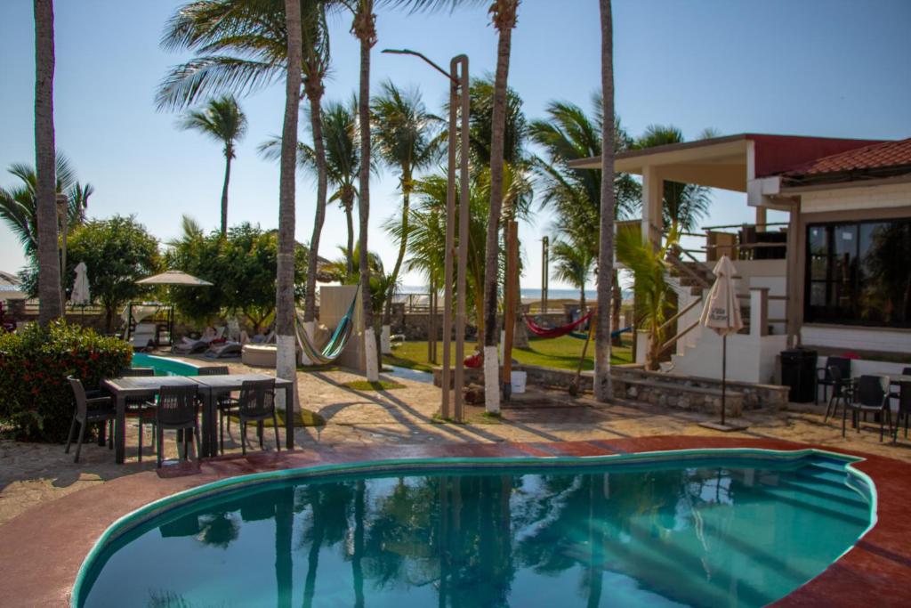 a beach with a pool, chairs, and a pool table at Hotel Villa Murano in Puerto Arista