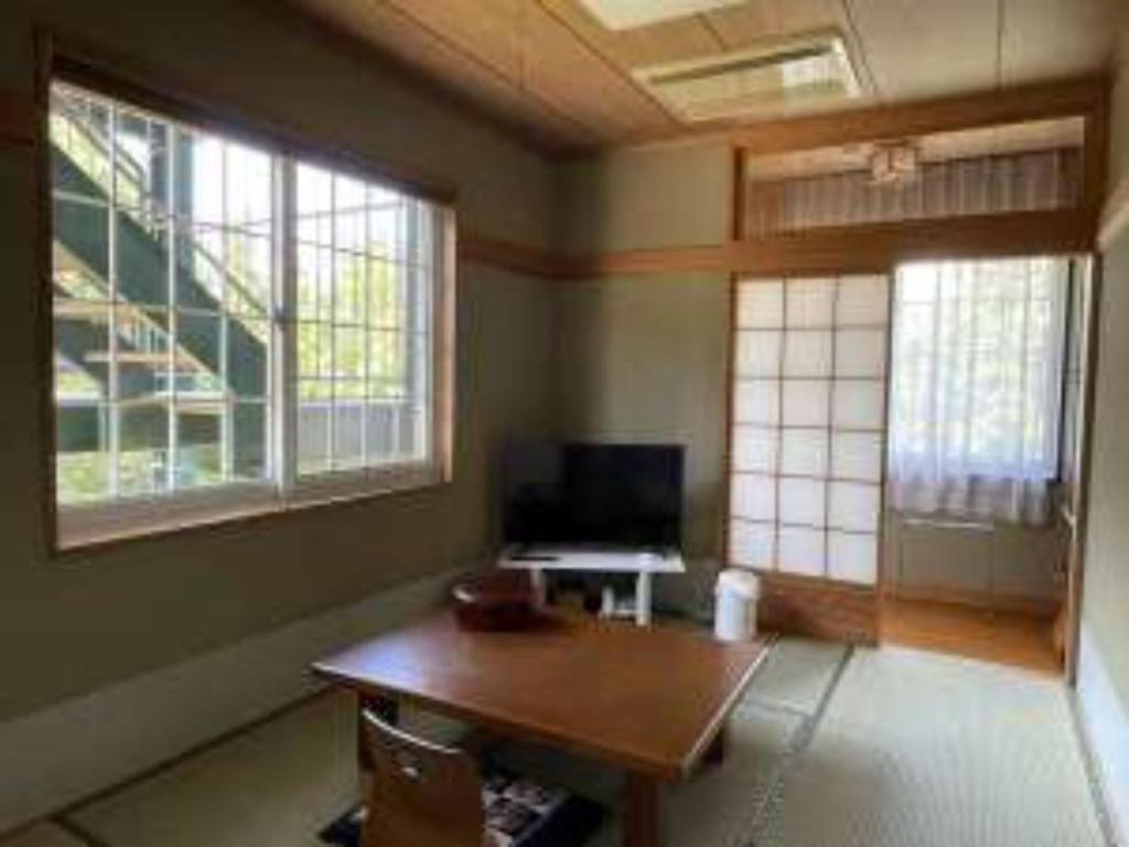 a room with a wooden table and two windows at Koguriyama Sanso - Vacation STAY 37452v in Minami Uonuma