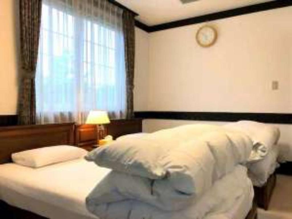 Koguriyama Sanso - Vacation STAY 37442v في Minami Uonuma: غرفة نوم مع سرير مع ساعة على الحائط