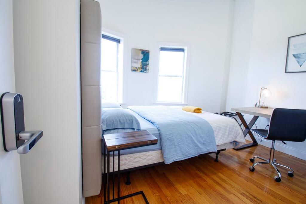 a bedroom with a bed and a desk and two windows at 4BR 1,5BH Comfy Newly Renovated Apt in Boston