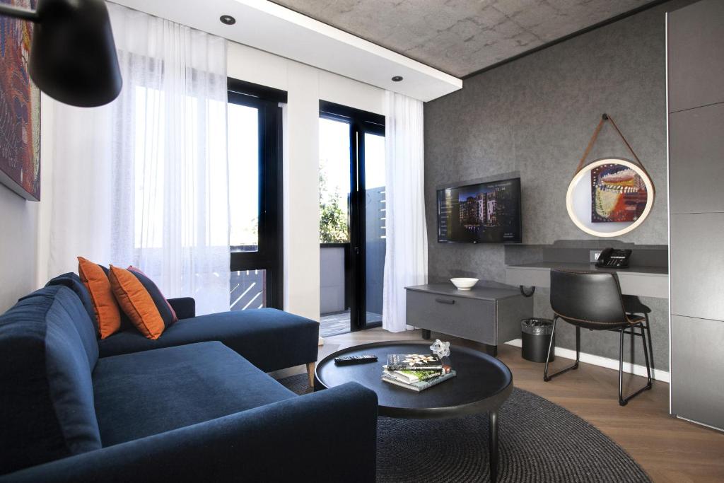 een woonkamer met een blauwe bank en een tafel bij Bridgewater Apartments by Century City Hotels in Kaapstad