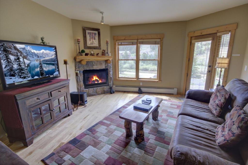 ein Wohnzimmer mit einem Sofa, einem TV und einem Kamin in der Unterkunft Tenderfoot Lodge 2613 in Keystone