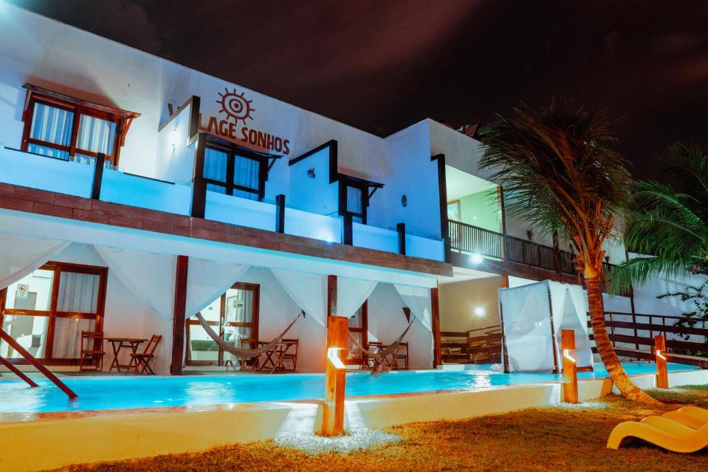 a large white building with a swimming pool at night at Pousada Village Sonhos Camocim in Camocim