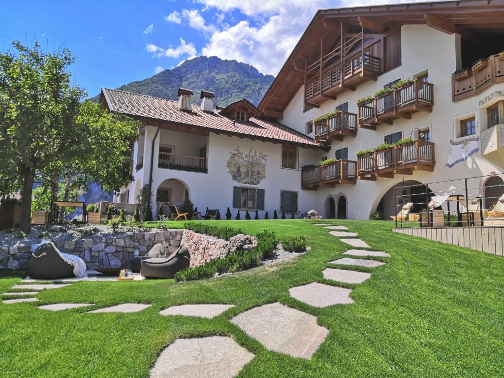 una casa con un césped verde delante de ella en Garnì Lilly en San Lorenzo in Banale