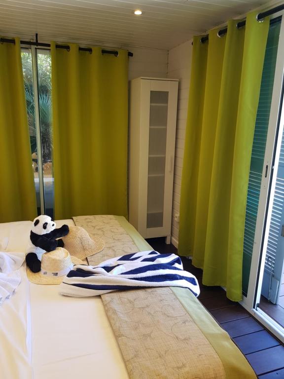 a bedroom with green curtains and a bed with a stuffed animal on it at Hotel Villa Maya in Saint-Tropez