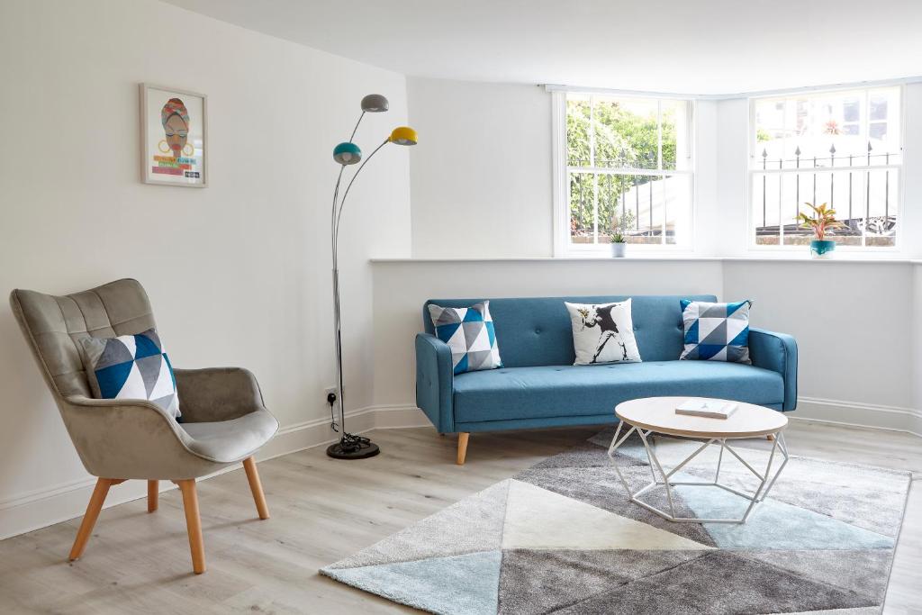 a living room with a blue couch and a chair at Stylish, spacious flat with private parking in Bristol
