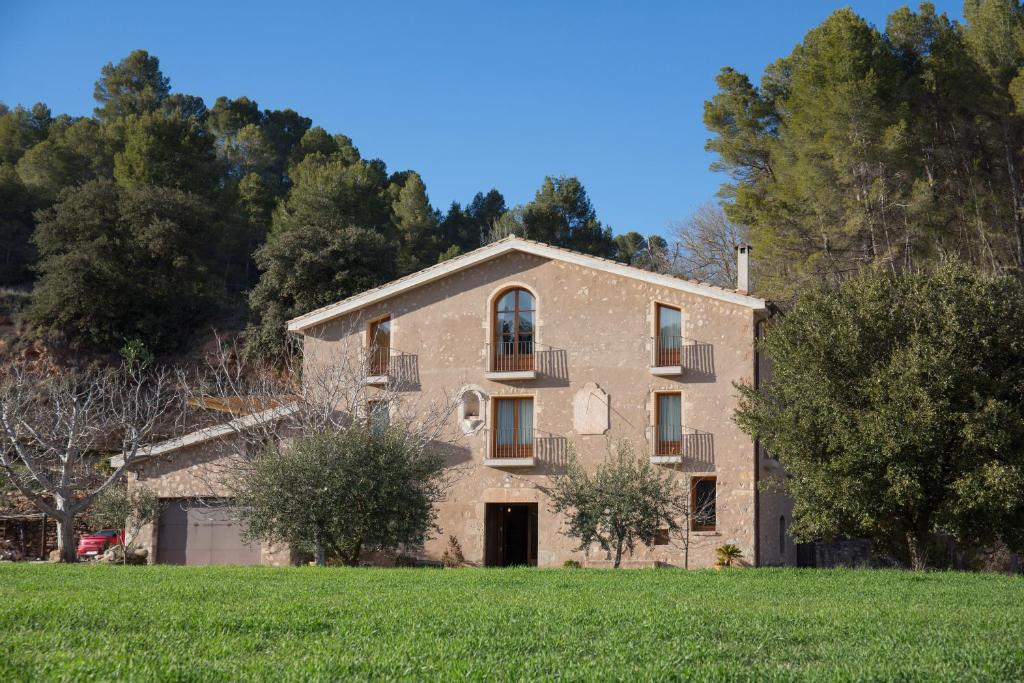 un gran edificio de piedra en un campo con árboles en Masia Els Nocs, en Jorba