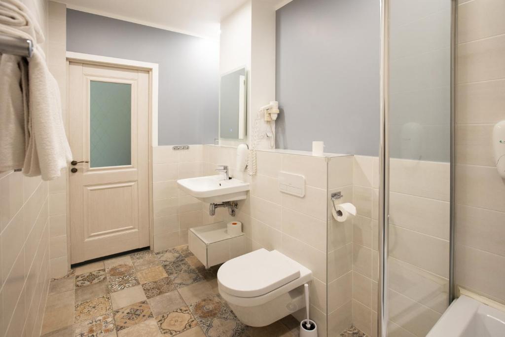 a white bathroom with a toilet and a sink at Hotel St. Barbara in Tallinn