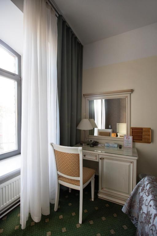 a bedroom with a desk with a chair and a mirror at Hotel St. Barbara in Tallinn