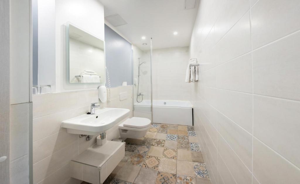 a white bathroom with a sink and a toilet at Hotel St. Barbara in Tallinn