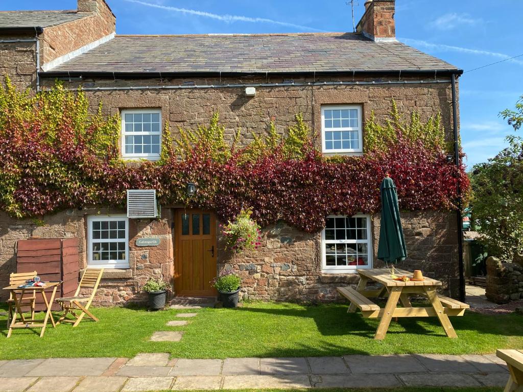 een huisje met een picknicktafel ervoor bij Gatesgarth Cottage @ The Pheasant Inn in Brampton