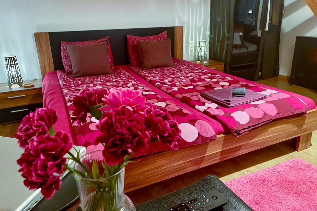 1 cama grande con sábanas rosas y un jarrón de flores en La Stella di Budapest, en Budapest