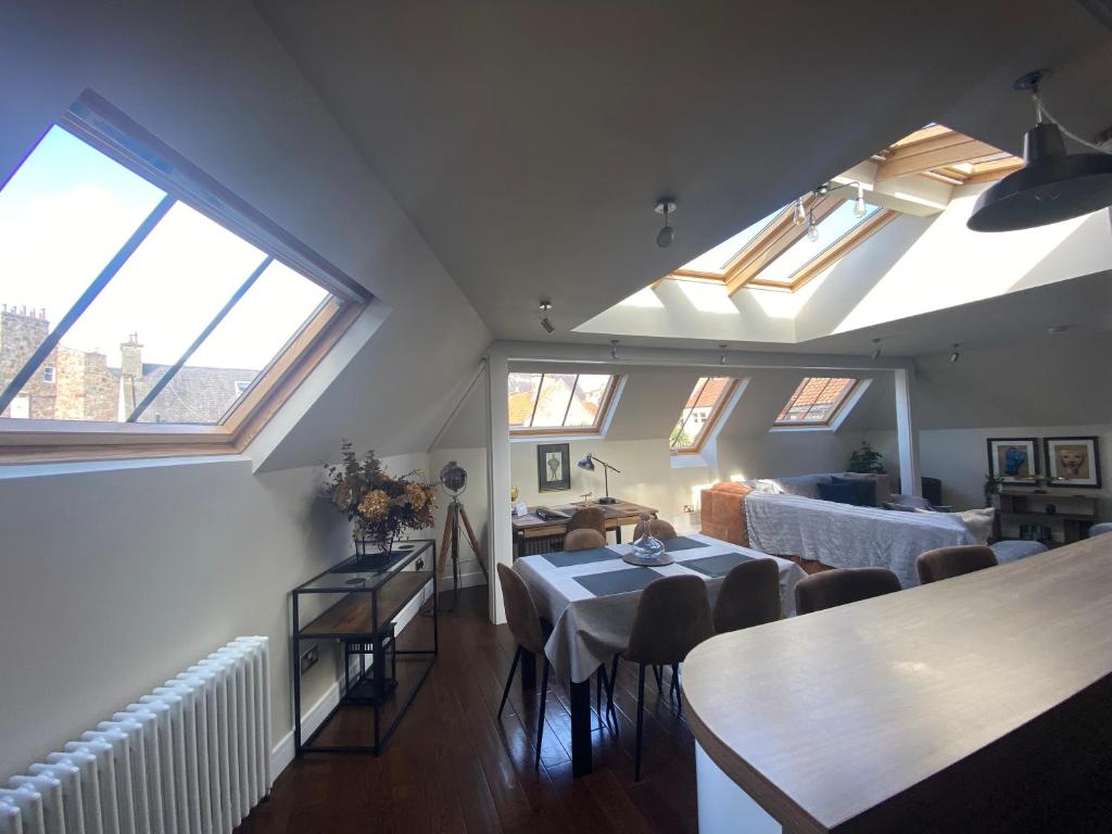 uma sala de estar com uma mesa e algumas janelas em The Loft - Remarkable 2-Bed Anstruther Apartment em Anstruther