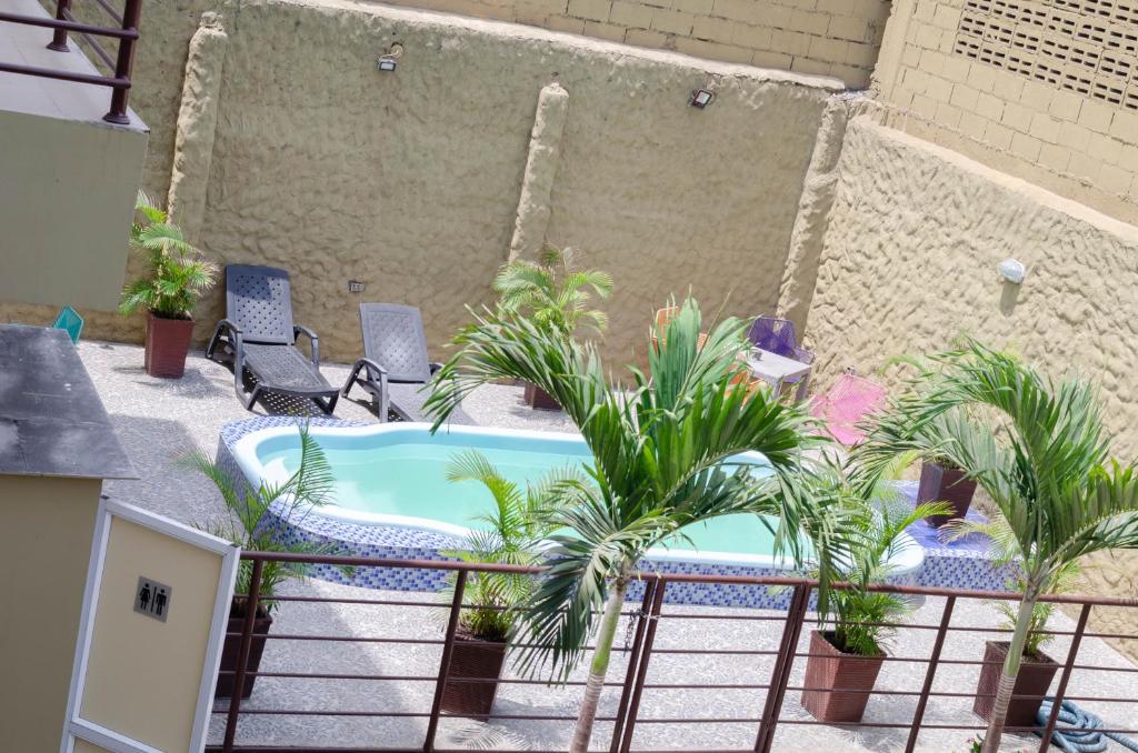 a patio with a pool with palm trees and chairs at Apartahotel y Hotel Sofichic Boutique in Barranquilla