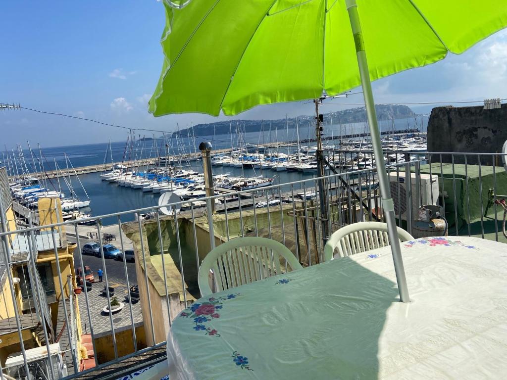 a table with a green umbrella on a balcony with boats at Procida Marina Grande in Procida