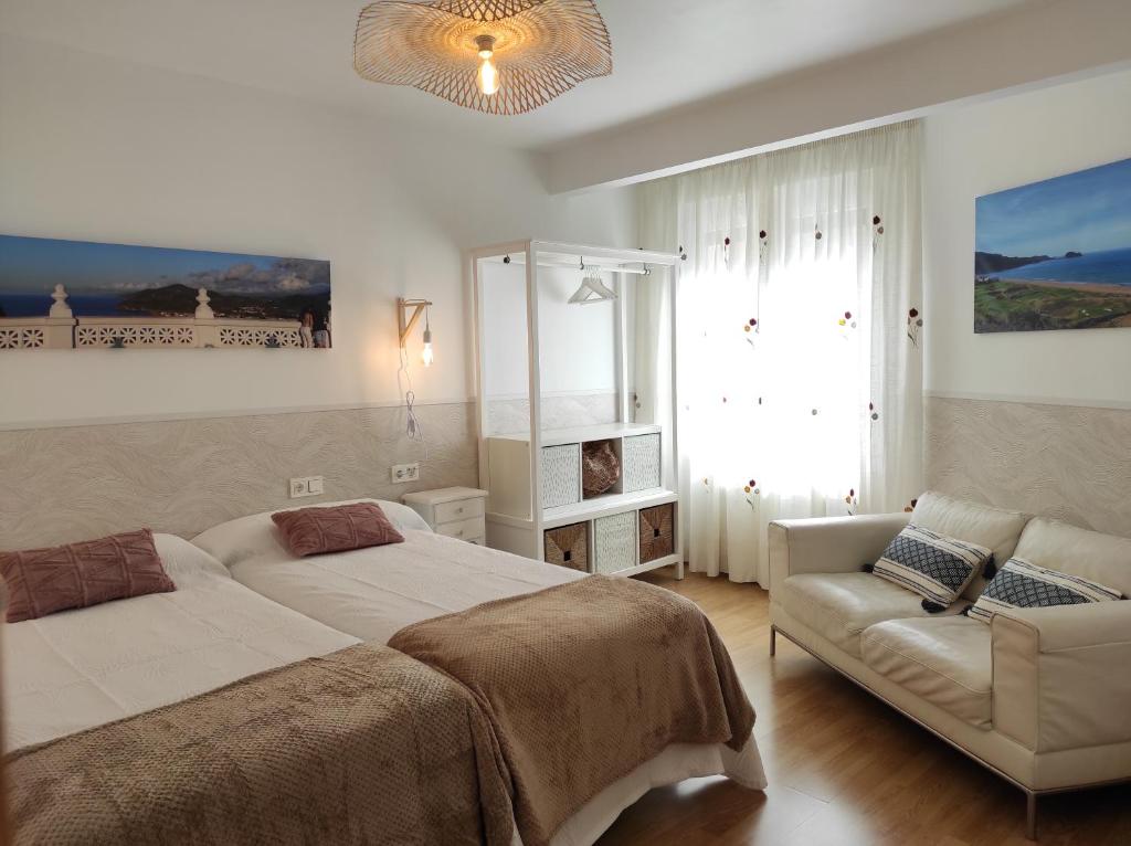 a bedroom with two beds and a couch and a chandelier at Kaixo Salegi Piso centro 2h-Salon-2wc-Parking-ESS02940 in Zarautz