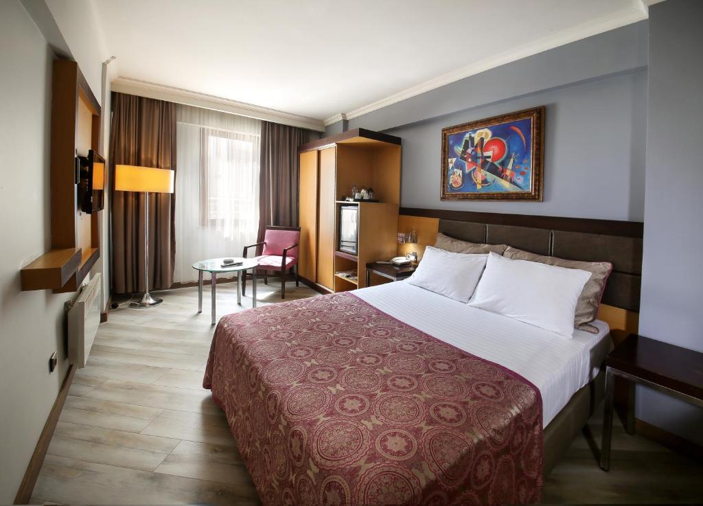 バルケスィルにあるElit Asya Hotelの大きなベッドとテーブルが備わるホテルルームです。