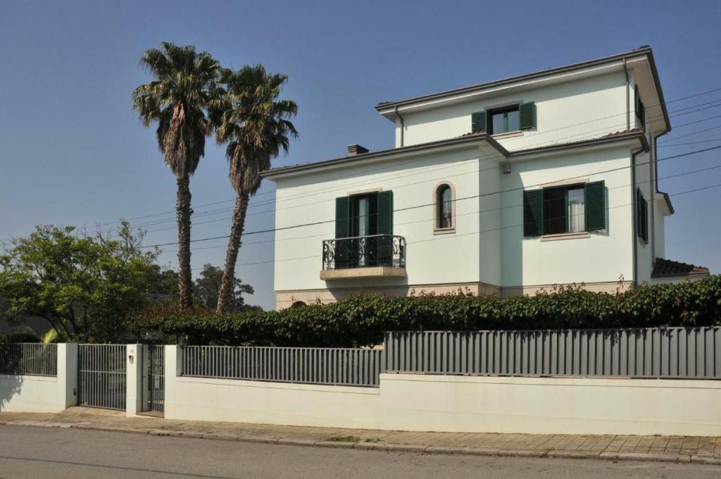 a white house with a fence and palm trees at Francelos Village in Vila Nova de Gaia