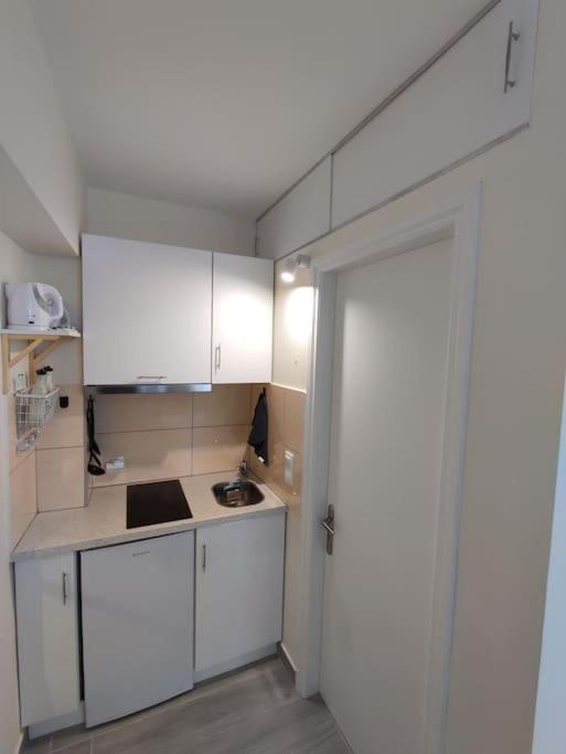a kitchen with white cabinets and a sink and a door at Vatos Studio in Vátos