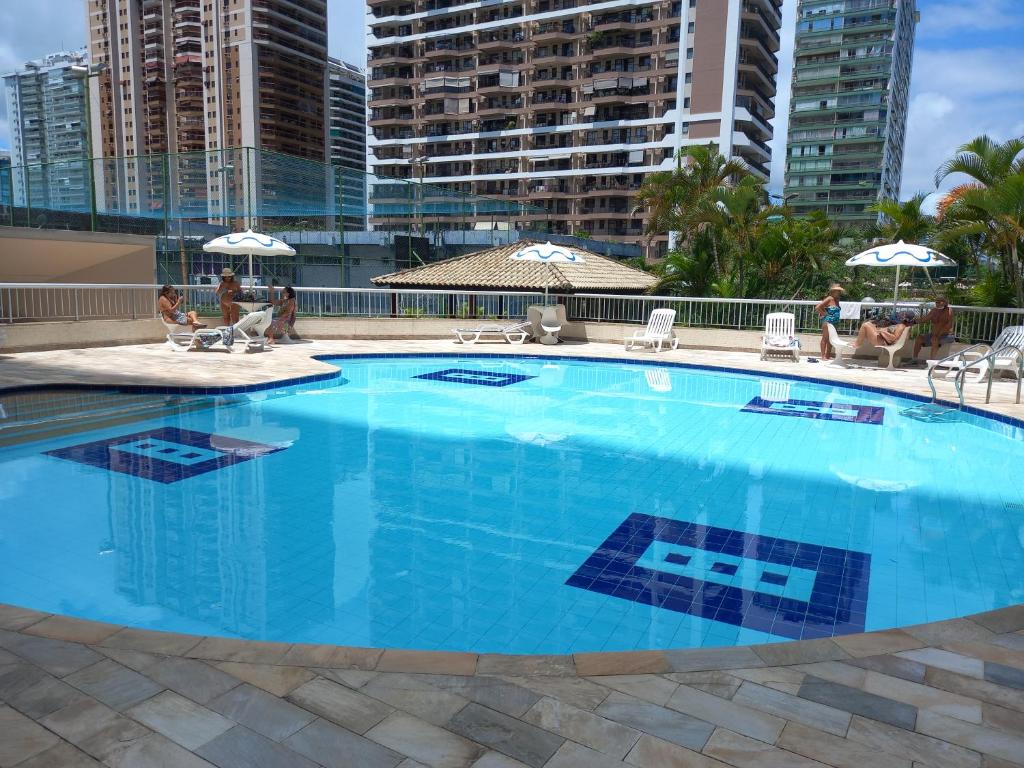 una gran piscina azul con edificios en el fondo en SEU CANTINHO NA BARRA en Río de Janeiro