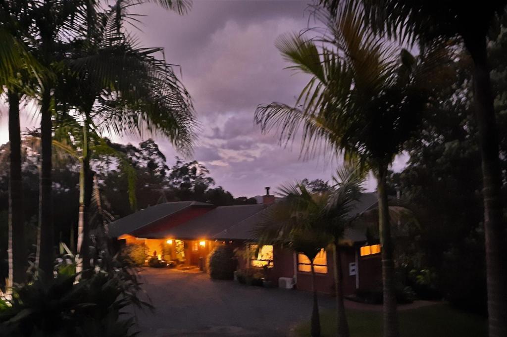 a house lit up at night with palm trees at Riverside Homestead in Paihia