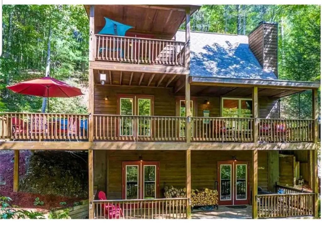 una grande casa in legno con ponti e ombrellone di Amazing Creek View Cabin w/ Hot Tub, Firepit & Pool Table a Ellijay