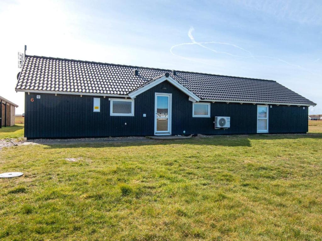 ein schwarzes Haus mit einem Rasenplatz davor in der Unterkunft 10 person holiday home in Harbo re in Harboør