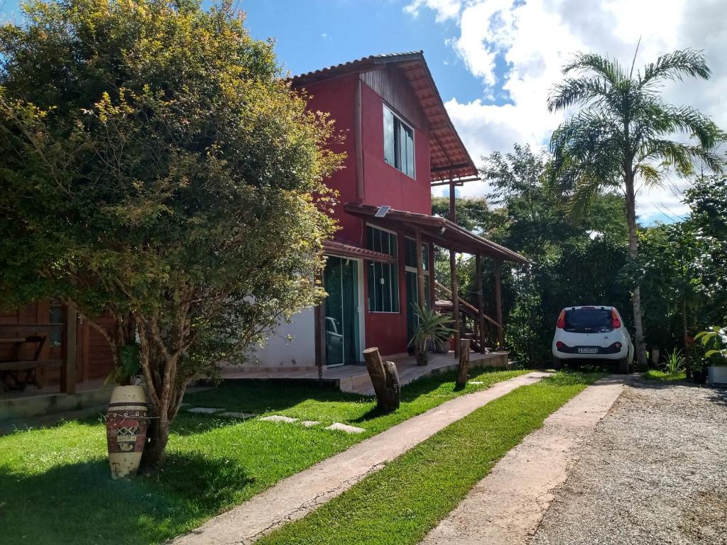 una casa roja con un coche blanco estacionado al lado en Loft da Serra e Kitnet na Serra en Nova Friburgo