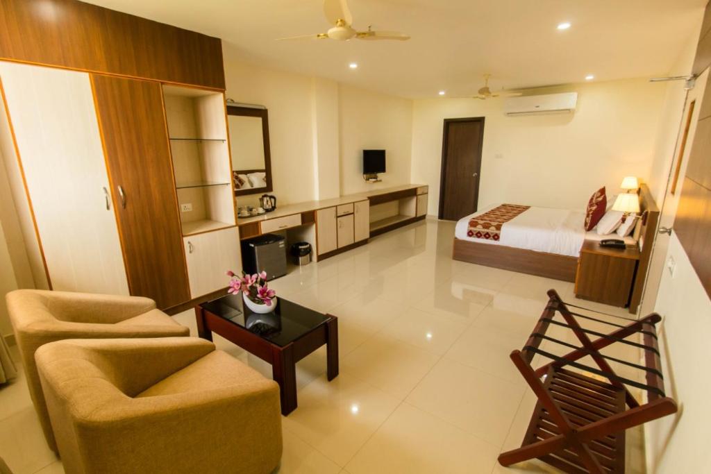 a living room with a bed and a couch and a table at Miracle Residency in Kizhake Chālakudi