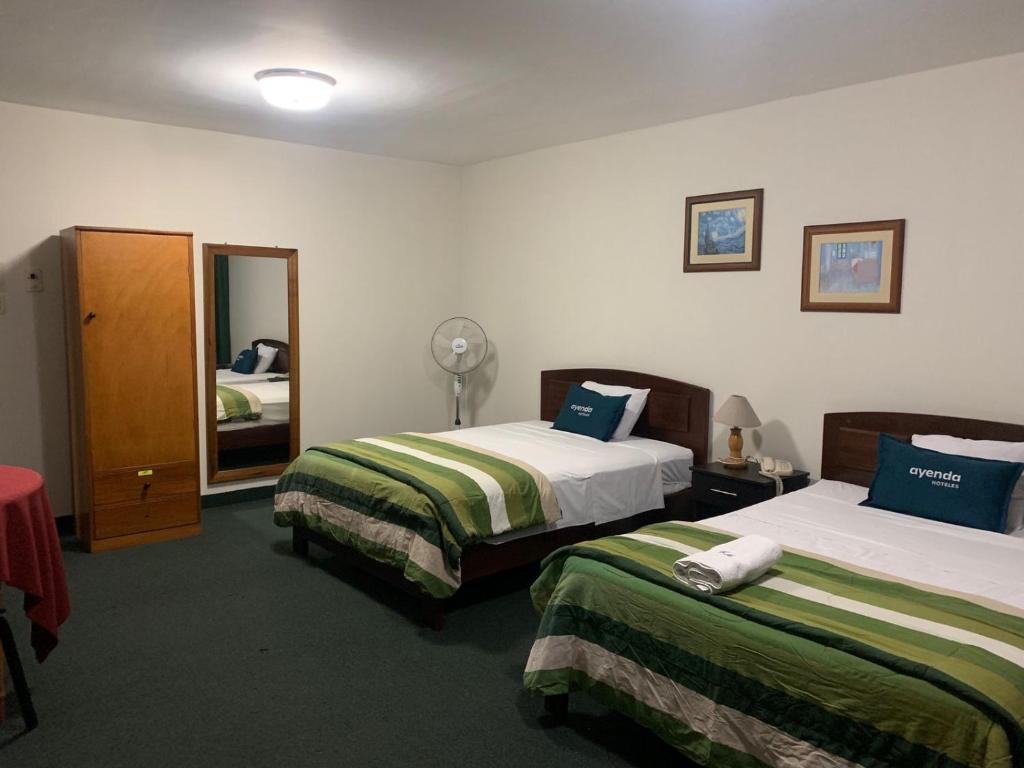 a hotel room with two beds and a mirror at Hotel Las Mercedes in Trujillo