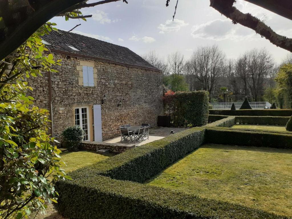 ein Steinhaus mit einer Bank im Garten in der Unterkunft Gîte Carsac-Aillac, 3 pièces, 4 personnes - FR-1-616-257 in Carsac-Aillac