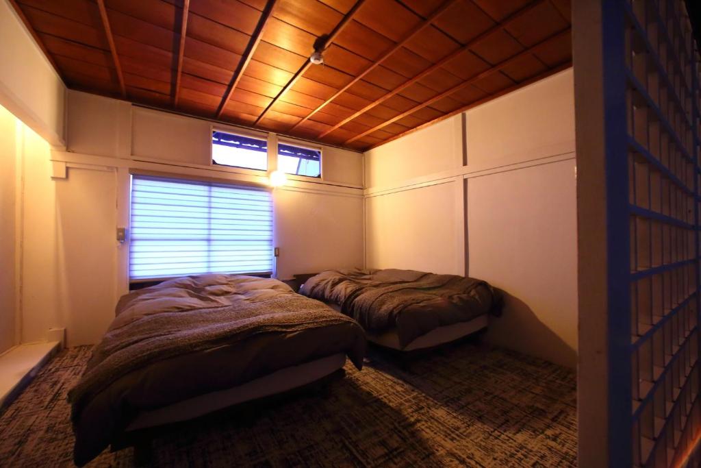 宮島にあるHEM'S HOTEL 1日1組限定 newの木製の天井が特徴のベッドルーム1室(ベッド2台付)