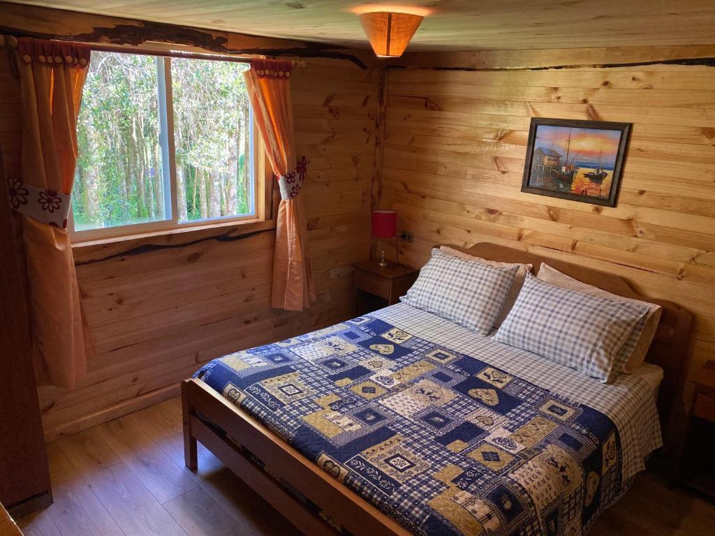 1 dormitorio con 1 cama en una cabaña de madera en Cabañas Los Fabianes, en Castro