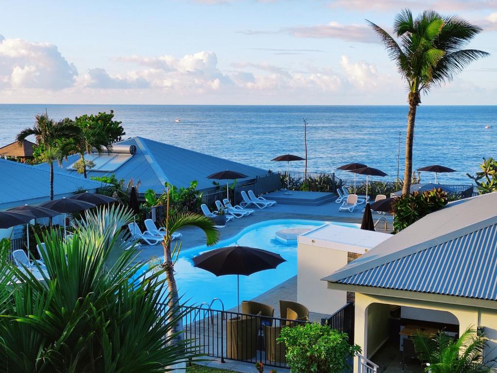 a pool with chairs and umbrellas next to the ocean at Hotel Exsel Victoria in Saint-Pierre