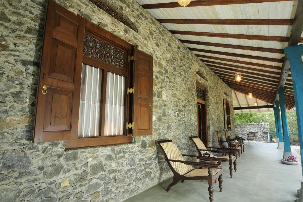 a porch with rocking chairs and a wooden door at Stone Cottage in Kandy