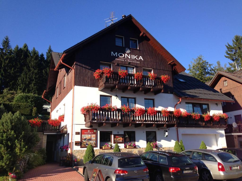 a large white building with flowers on the balcony at Pension and Apartments MONIKA in Špindlerův Mlýn