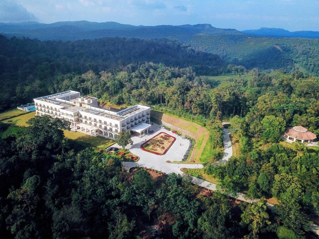 Montrose Golf Resort and Spa - Coorg في Jambur: منظر جوي لمبنى في وسط غابة