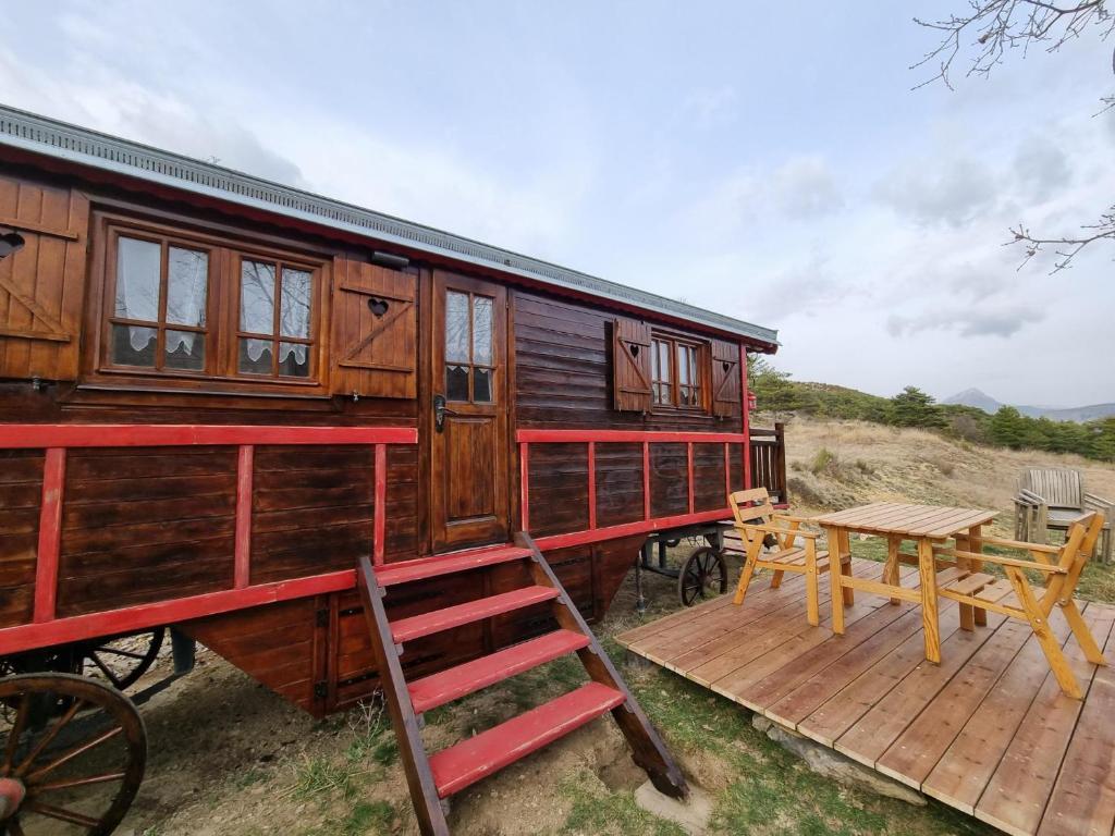 a wooden train car with a wooden deck and a table at Roulotte du domaine de la Graou in La Palud sur Verdon