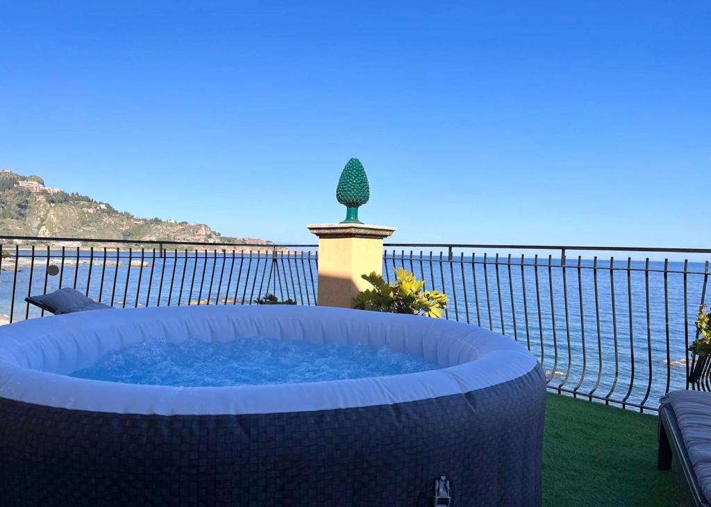 ジャルディーニ・ナクソスにあるMiriam Sea Front Apartment Jacuzziの海の景色を望むパティオ(大型ホットタブ付)