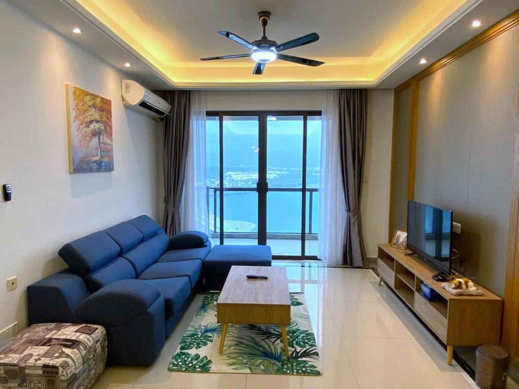 uma sala de estar com um sofá azul e uma televisão em R&F Princess Cove JB Apartment Suites By SC Homestay em Johor Bahru