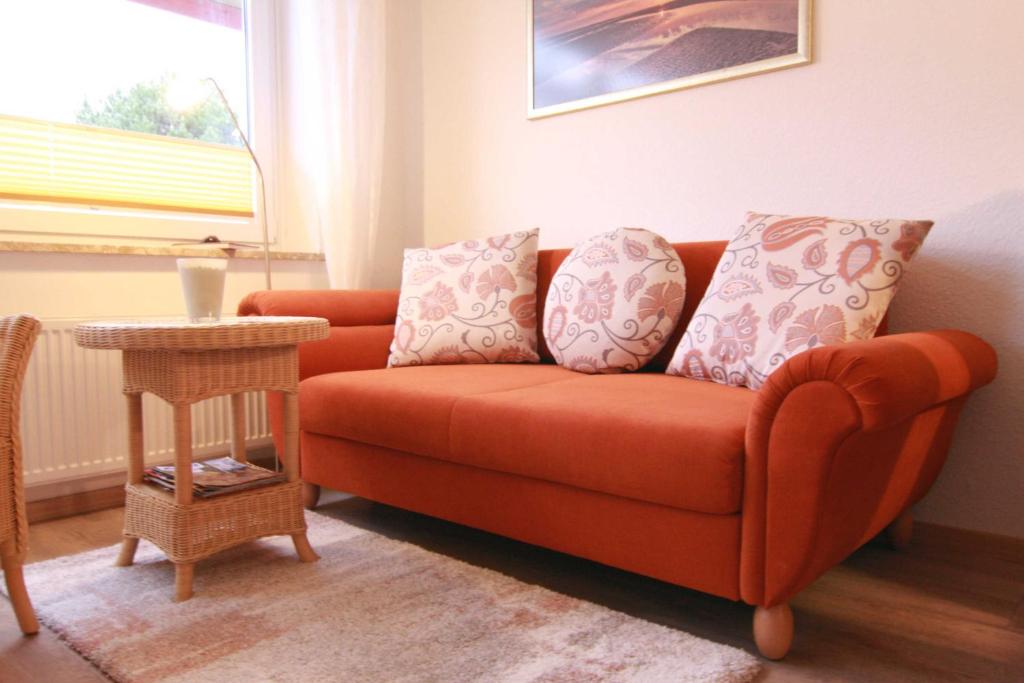 - un canapé orange dans le salon avec une table dans l'établissement Vogelsand 324, à Cuxhaven
