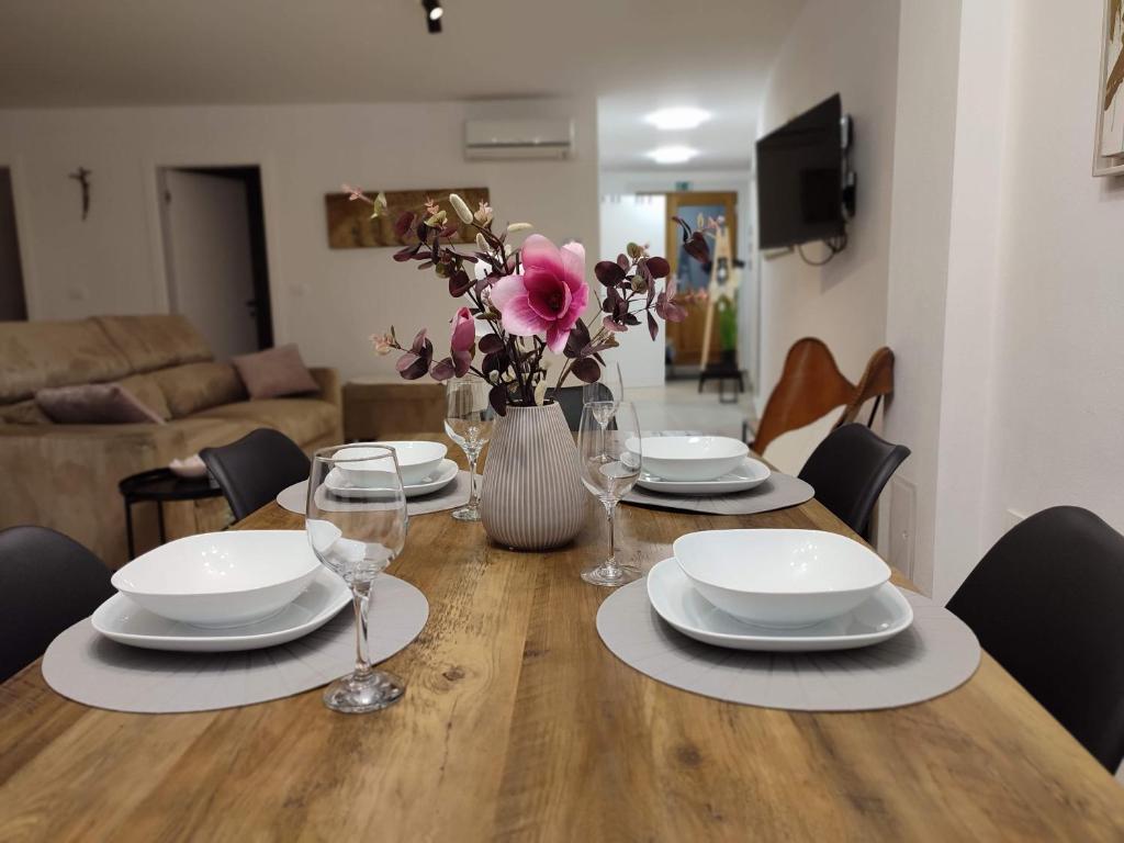 einen Tisch mit Tellern und Gläsern und eine Vase mit Blumen in der Unterkunft Apartment Lucky in Izola