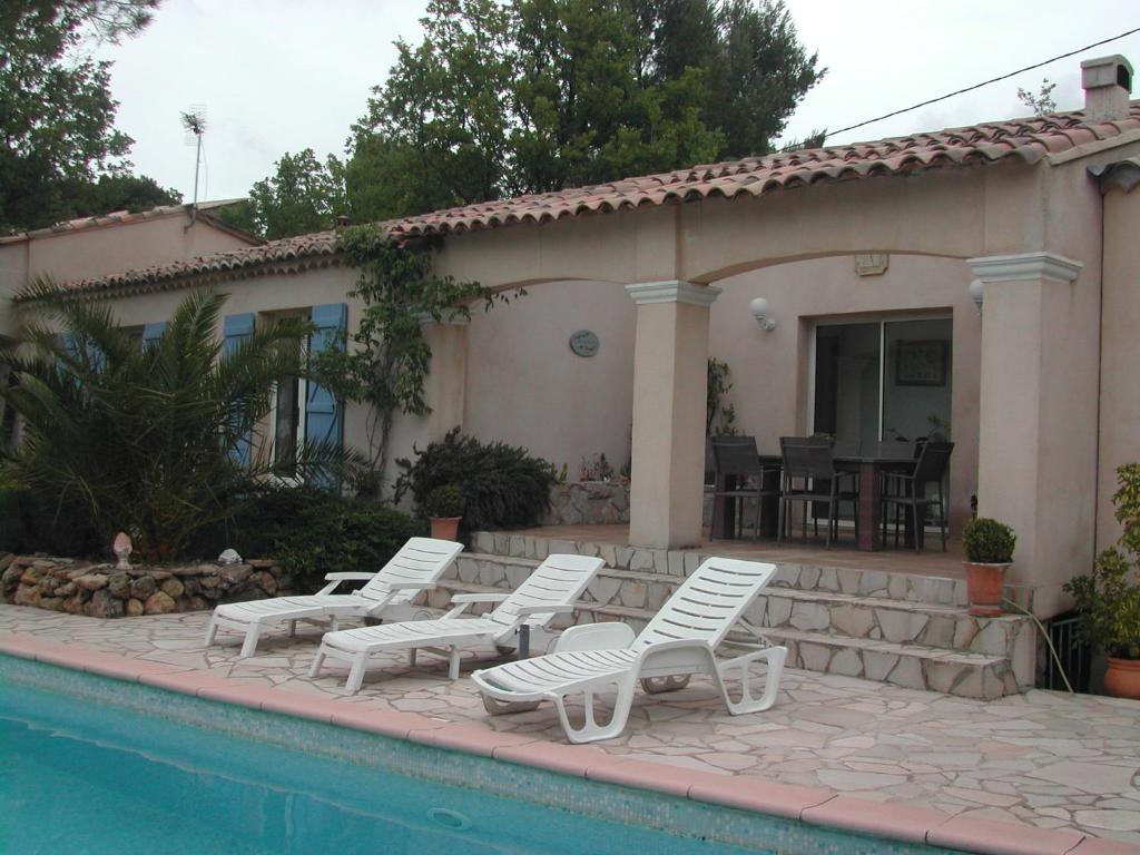 un groupe de chaises de jardin blanches assises à côté d'une maison dans l'établissement le patio, à Tourtour