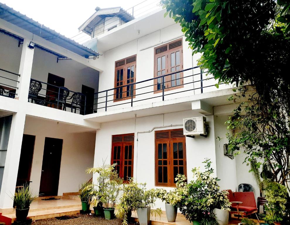 een wit huis met rode deuren en een balkon bij Emarald Holiday Homes in Anuradhapura