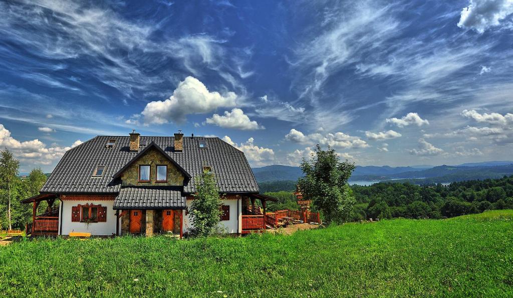 a house sitting on top of a green hill at Beskidnik in Polańczyk