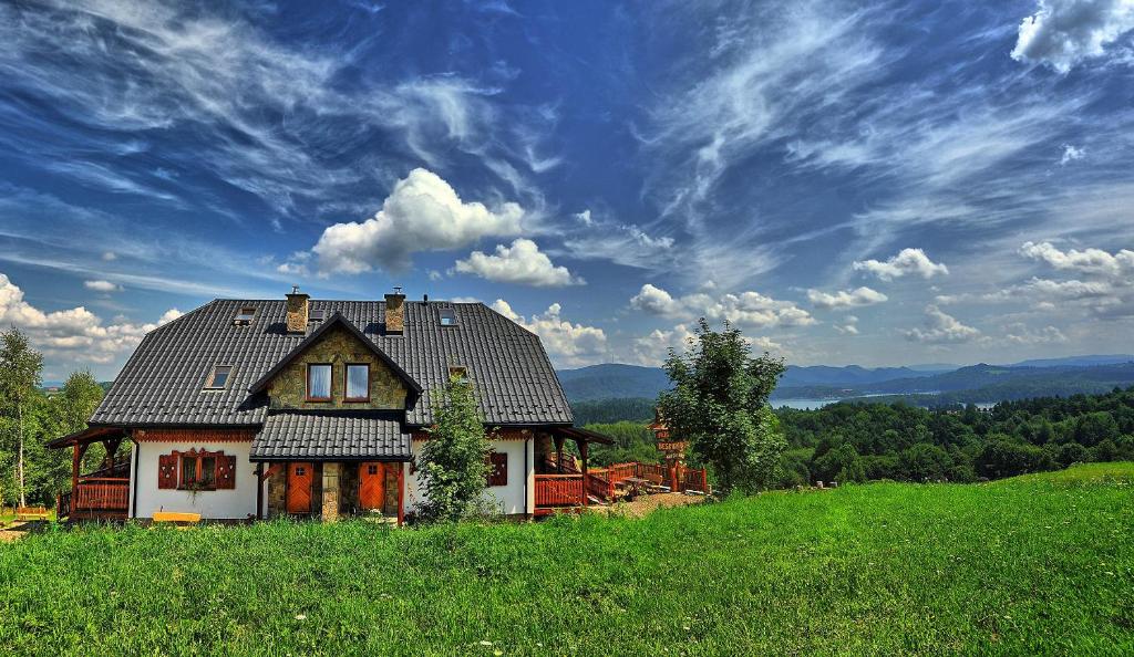 une maison assise au sommet d'une colline verdoyante dans l'établissement Beskidnik, à Polańczyk